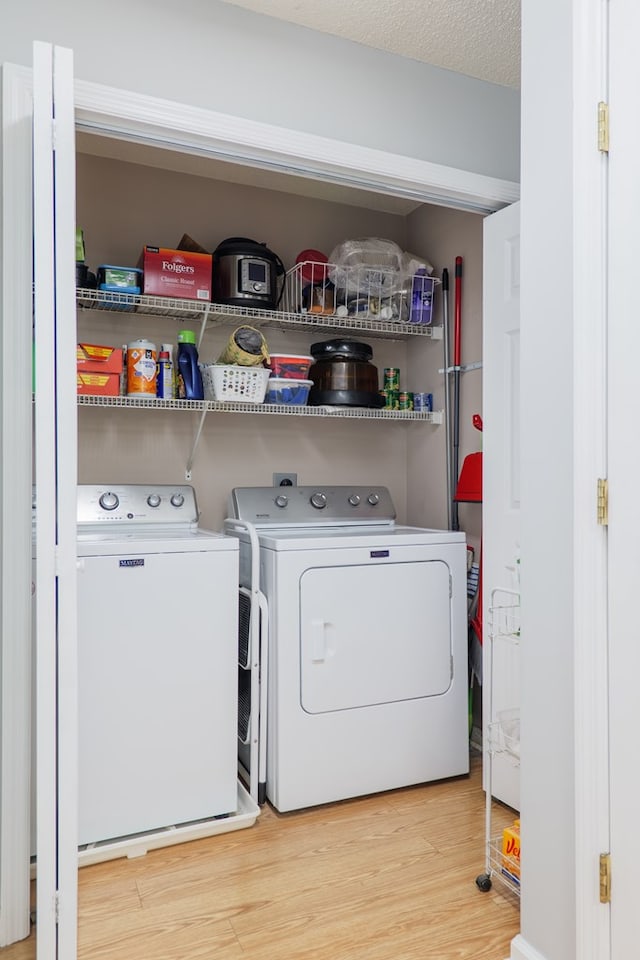 washroom featuring separate washer and dryer, laundry area, and wood finished floors