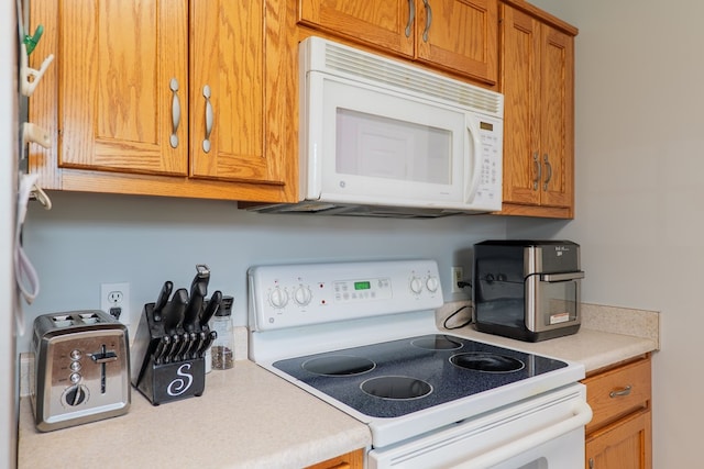 kitchen with light countertops, brown cabinets, and white appliances