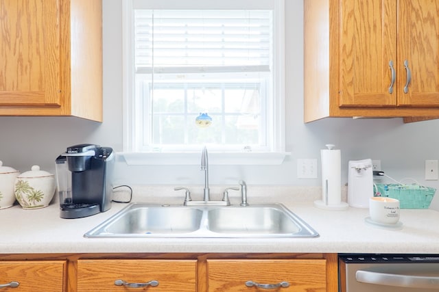 kitchen with stainless steel dishwasher, a sink, and light countertops