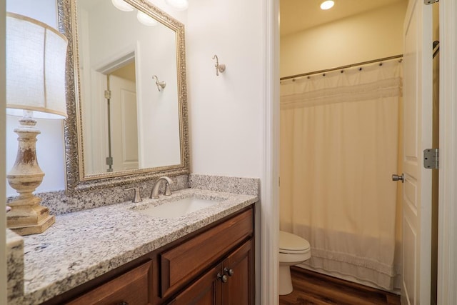 bathroom with toilet, vanity, and wood finished floors