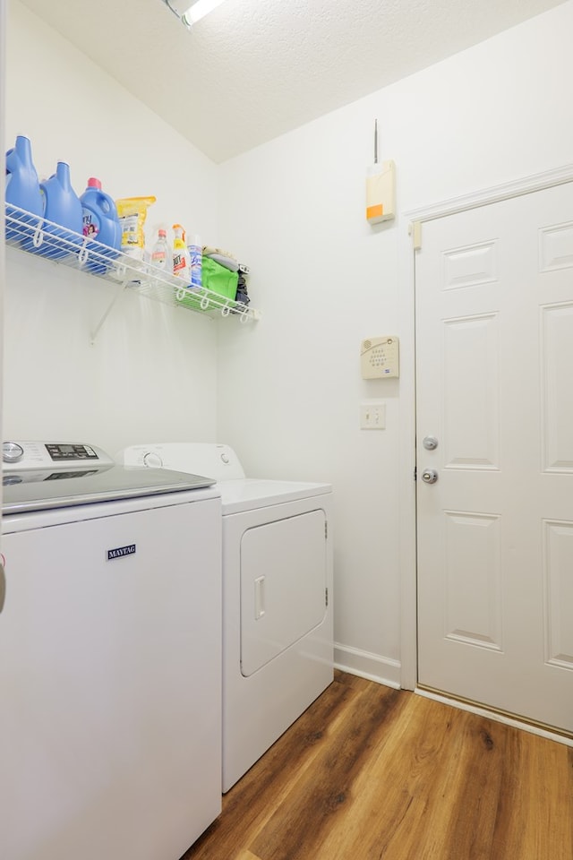 clothes washing area featuring laundry area, washer and dryer, baseboards, and wood finished floors