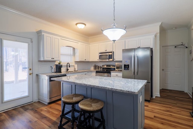 kitchen with stainless steel appliances, a kitchen bar, a kitchen island, and dark wood-style flooring