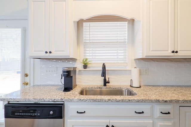 kitchen featuring a sink, tasteful backsplash, dishwasher, and white cabinetry