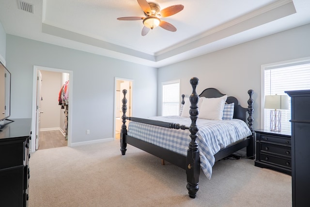 bedroom with visible vents, a raised ceiling, multiple windows, and light carpet