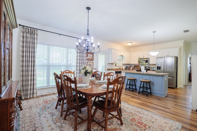 dining space with crown molding, a notable chandelier, light wood-style floors, and visible vents