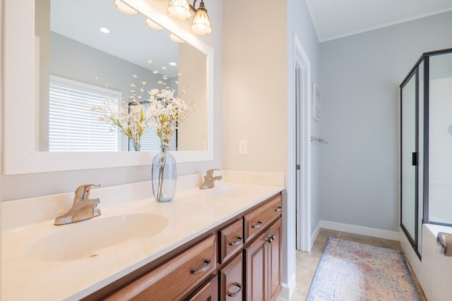 full bath with double vanity, a shower stall, baseboards, and a sink