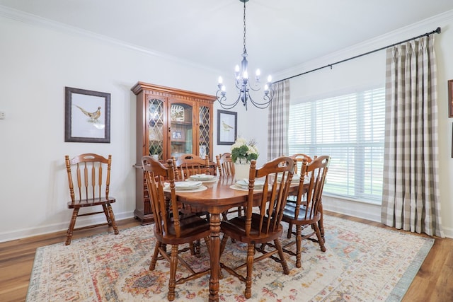 dining room featuring light wood-style flooring, baseboards, a notable chandelier, and ornamental molding