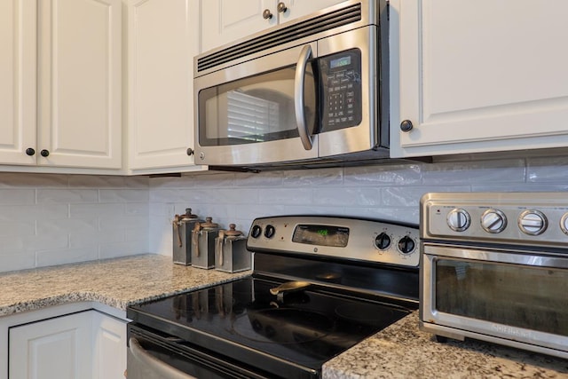 kitchen with stainless steel appliances, white cabinets, and decorative backsplash