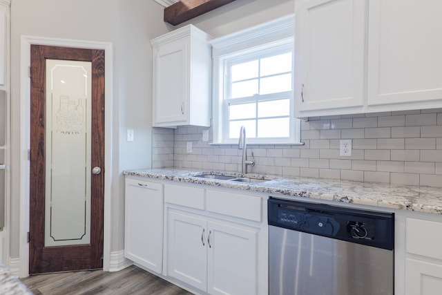 kitchen with tasteful backsplash, white cabinetry, sink, stainless steel dishwasher, and light wood-type flooring