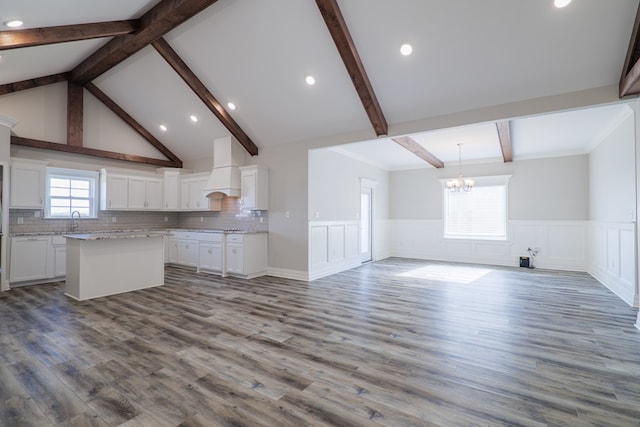 kitchen with white cabinetry, a kitchen island, sink, and custom range hood