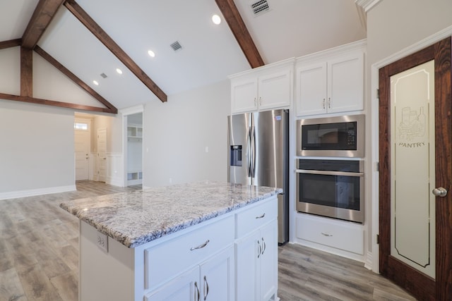 kitchen with light stone counters, a center island, light wood-type flooring, stainless steel appliances, and white cabinets