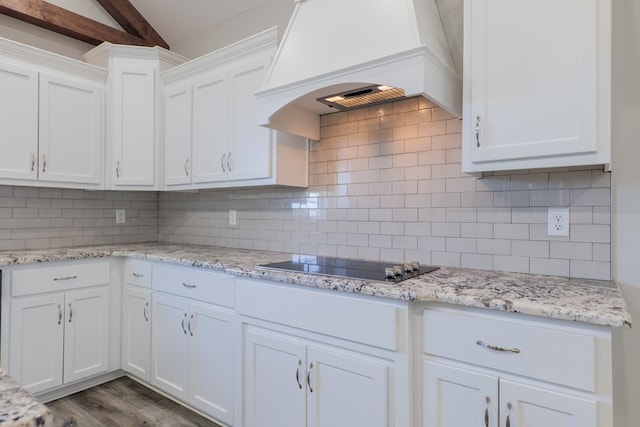 kitchen with custom range hood, black electric stovetop, white cabinets, and backsplash