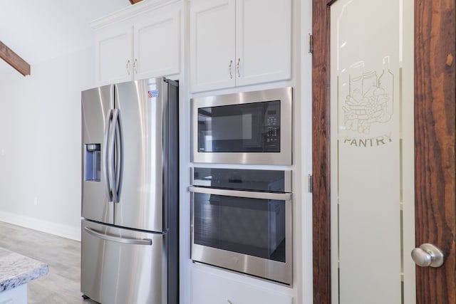 kitchen featuring light stone counters, appliances with stainless steel finishes, light wood-type flooring, and white cabinets