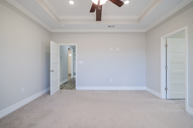 carpeted spare room featuring ornamental molding, a raised ceiling, and ceiling fan