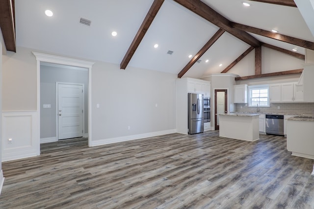 kitchen featuring beamed ceiling, appliances with stainless steel finishes, a center island, and white cabinets