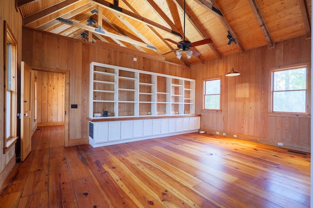 empty room with hardwood / wood-style flooring, wooden walls, and vaulted ceiling with beams