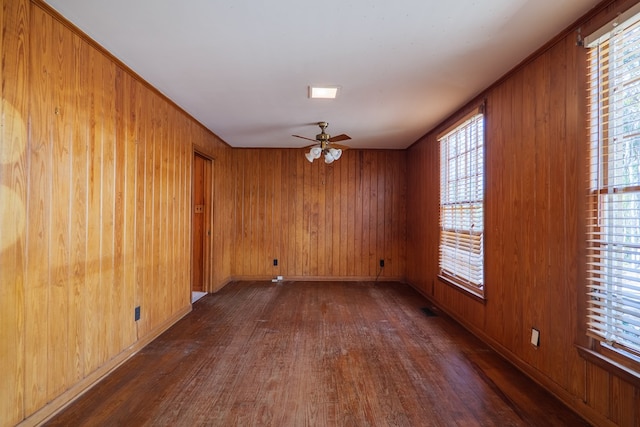 empty room featuring ceiling fan, wood walls, and dark hardwood / wood-style floors