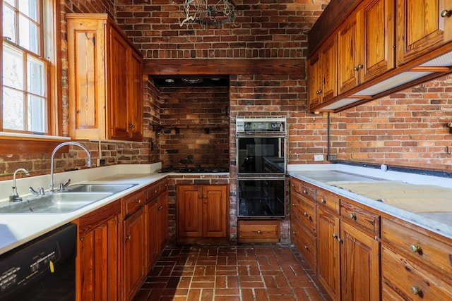 kitchen featuring brick wall, sink, and black appliances