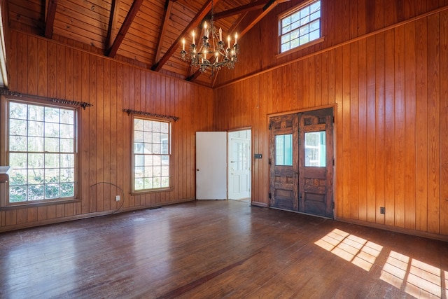 entrance foyer featuring a notable chandelier, beamed ceiling, dark wood-type flooring, and wood walls