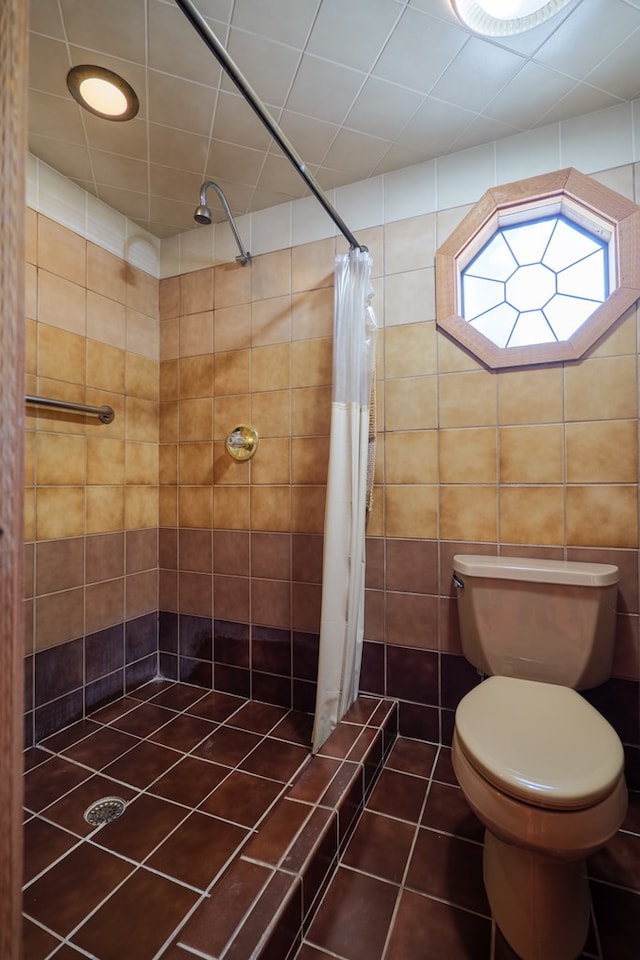 bathroom with toilet, tile walls, tile patterned flooring, and curtained shower