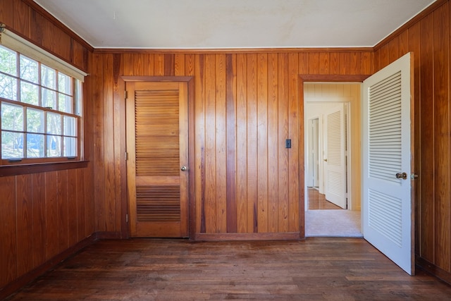 spare room featuring dark wood-type flooring and wooden walls