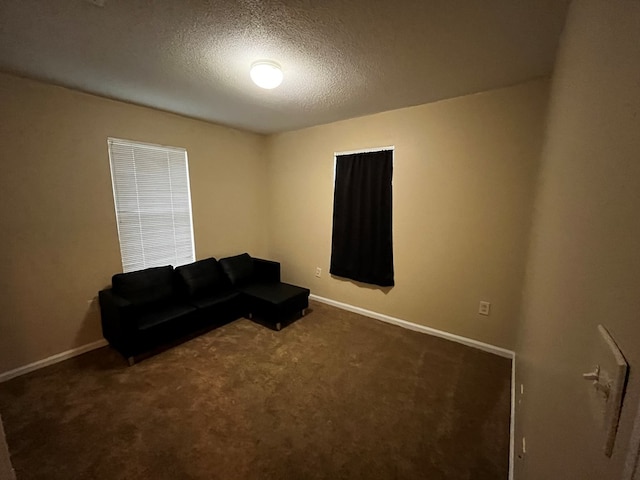 living area with dark colored carpet and a textured ceiling