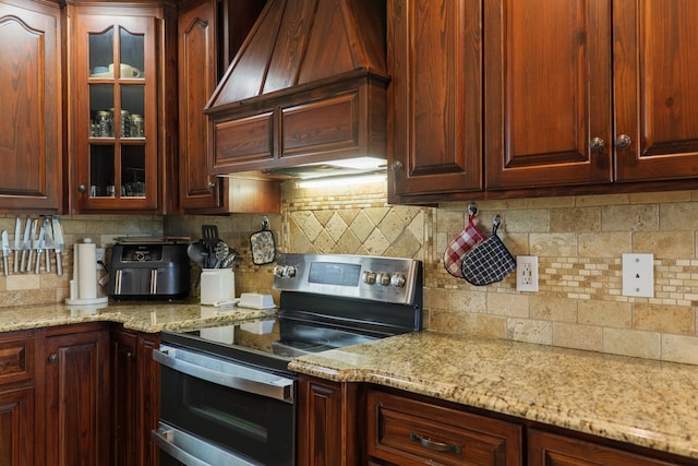 203 Murray Mccranie Rd, Norman Park, GA 31771 - kitchen with stainless steel range with electric stovetop, custom exhaust hood, decorative backsplash, and glass insert cabinets