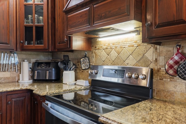 203 Murray Mccranie Rd, Norman Park, GA 31771 - kitchen with stainless steel range with electric cooktop, tasteful backsplash, glass insert cabinets, light stone counters, and custom range hood