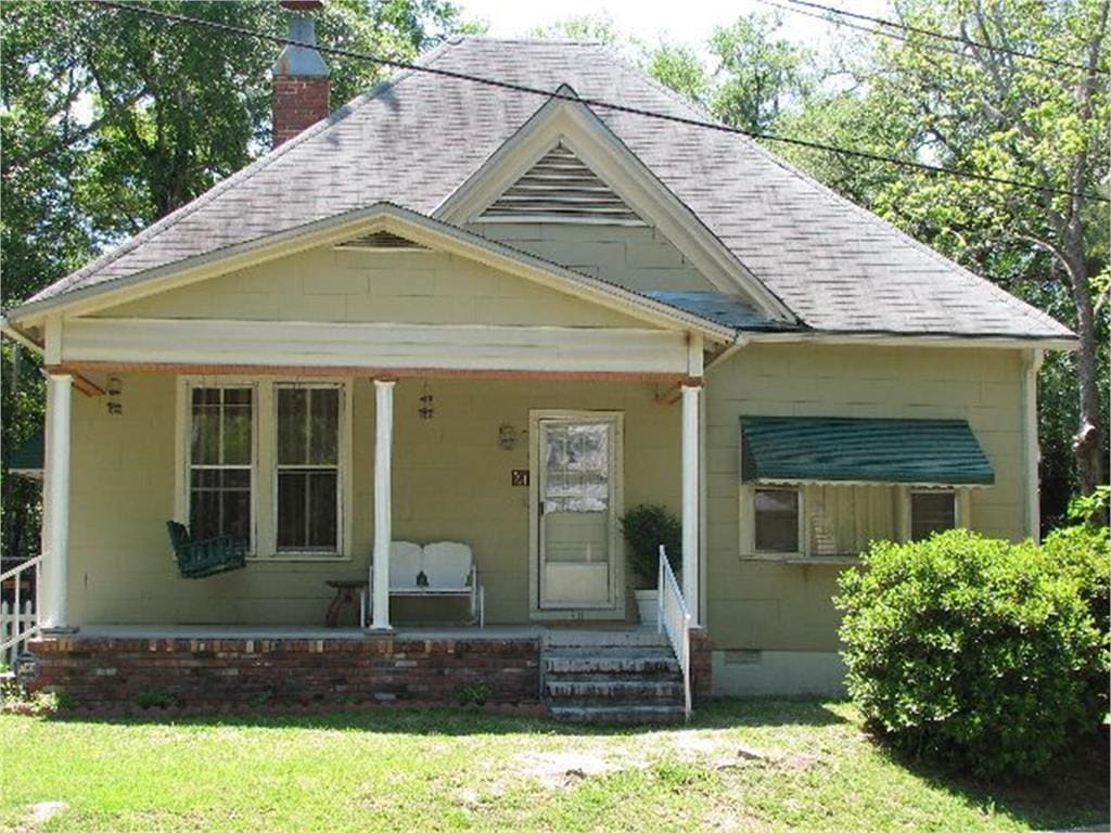 bungalow featuring a porch, crawl space, a chimney, and a front yard