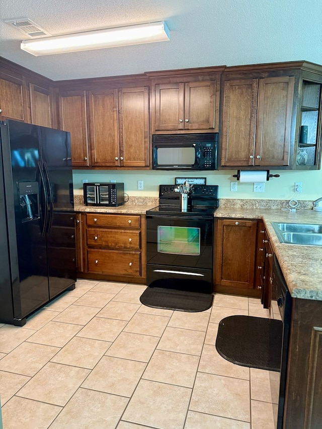 3650 Tupelo Rd, Valdosta, GA 31605 - kitchen with black appliances, a sink, light tile patterned flooring, a textured ceiling, and light stone countertops