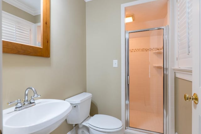 bathroom featuring crown molding, sink, a shower with door, and toilet