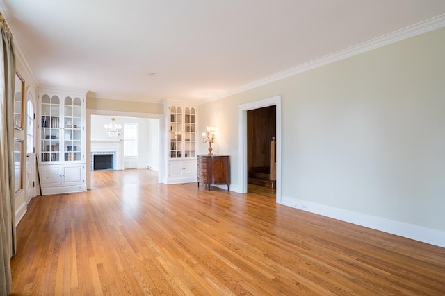 unfurnished living room featuring ornamental molding, a fireplace, and light hardwood / wood-style flooring