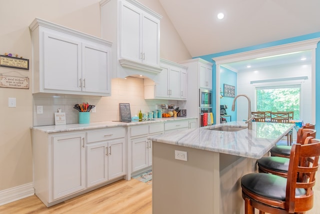 kitchen with white cabinetry, sink, and an island with sink