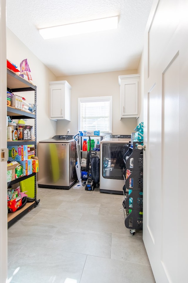 washroom featuring washing machine and dryer, cabinets, and a textured ceiling