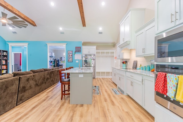 kitchen featuring white cabinetry, stainless steel appliances, and a center island with sink