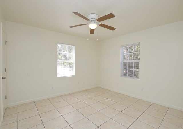 spare room featuring ceiling fan, a healthy amount of sunlight, and light tile patterned floors