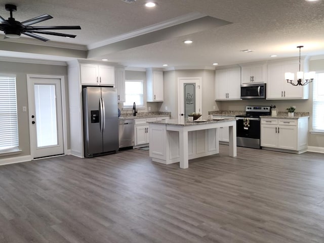 kitchen with white cabinetry, pendant lighting, stainless steel appliances, and a kitchen island