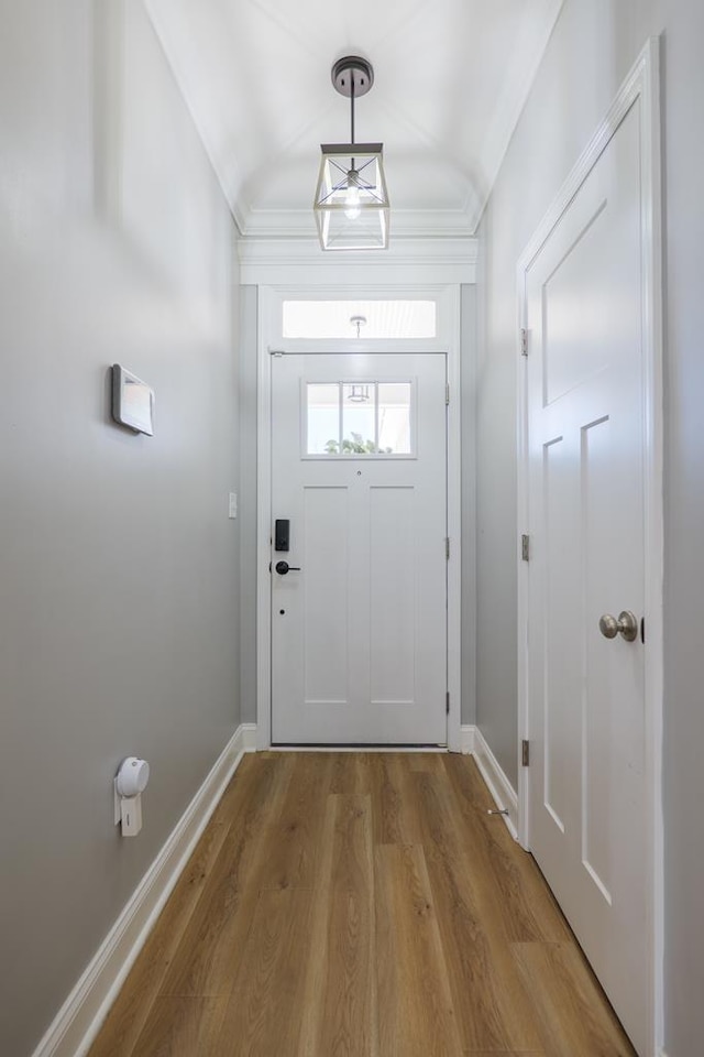 doorway to outside with baseboards, wood finished floors, and ornamental molding