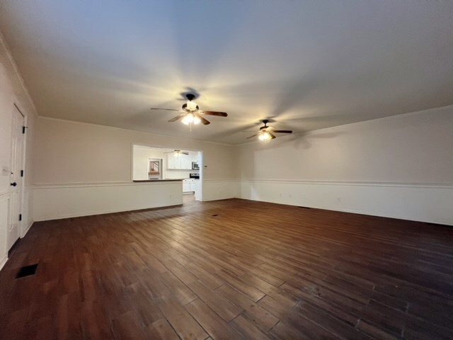 unfurnished living room featuring dark hardwood / wood-style floors and ceiling fan