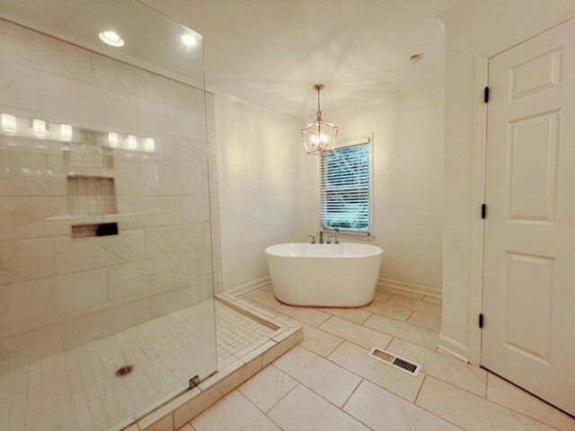 bathroom featuring tile patterned floors, a notable chandelier, and shower with separate bathtub