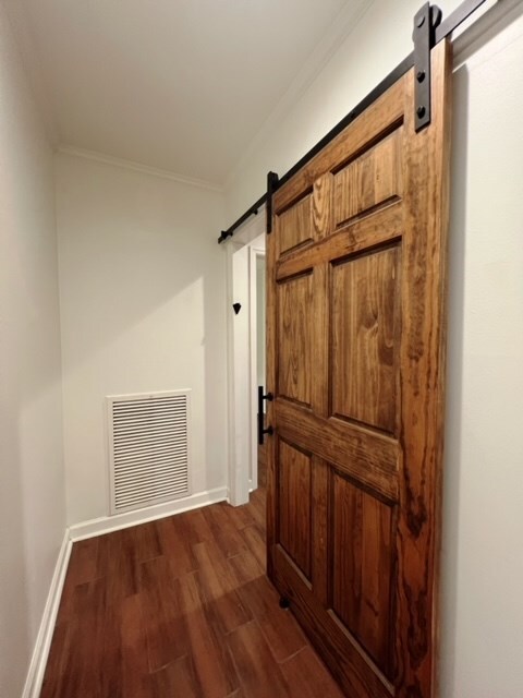 corridor featuring dark hardwood / wood-style flooring, a barn door, and ornamental molding