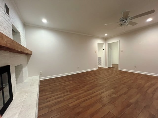 unfurnished living room featuring a fireplace, dark hardwood / wood-style floors, ceiling fan, and ornamental molding