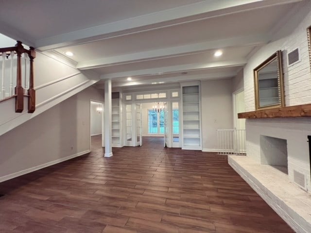 unfurnished living room featuring beam ceiling and dark wood-type flooring