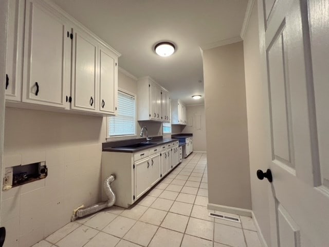 kitchen featuring crown molding, sink, white cabinets, and light tile patterned floors