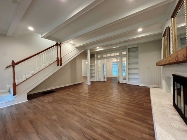 unfurnished living room with beamed ceiling and wood-type flooring