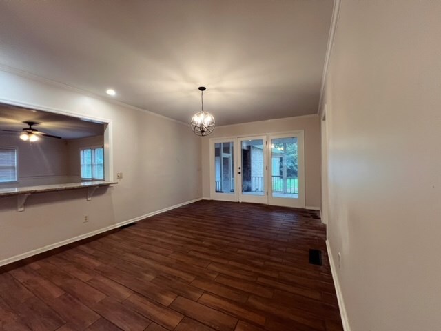 interior space featuring ceiling fan with notable chandelier, dark hardwood / wood-style floors, and ornamental molding