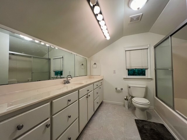 full bathroom featuring toilet, vanity, vaulted ceiling, and combined bath / shower with glass door