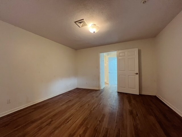 empty room with a textured ceiling and dark hardwood / wood-style floors