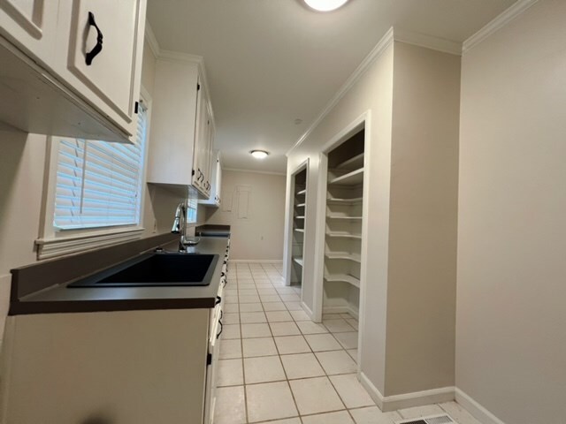 kitchen with white cabinets, light tile patterned floors, and ornamental molding