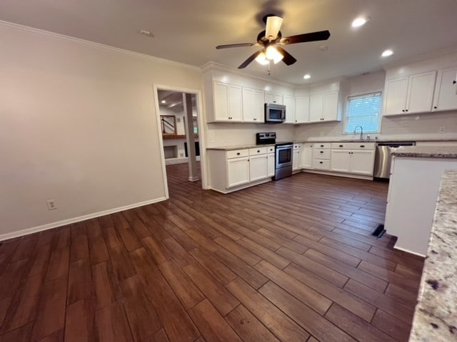 kitchen with white cabinets, appliances with stainless steel finishes, dark hardwood / wood-style flooring, and ceiling fan